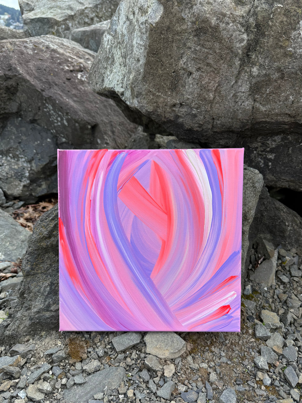 Abstract painting with pink and purple swirls on a rocky surface