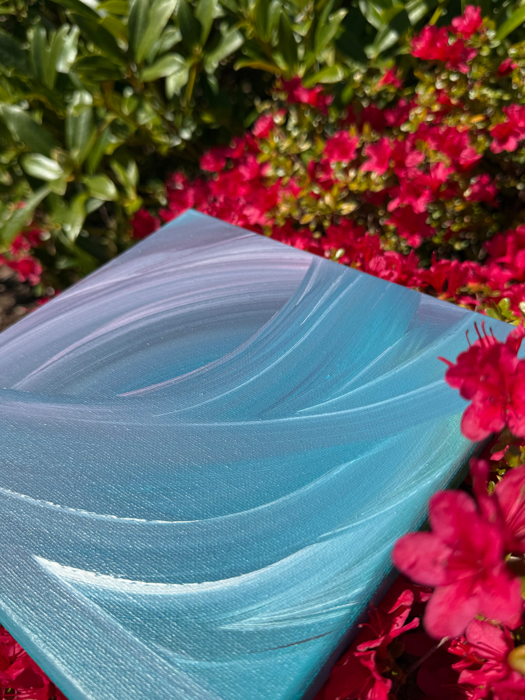 Blue fabric with wavy pattern against a background of pink flowers and green leaves