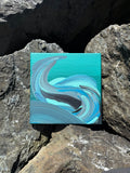Abstract painting on a small canvas placed on rocks
