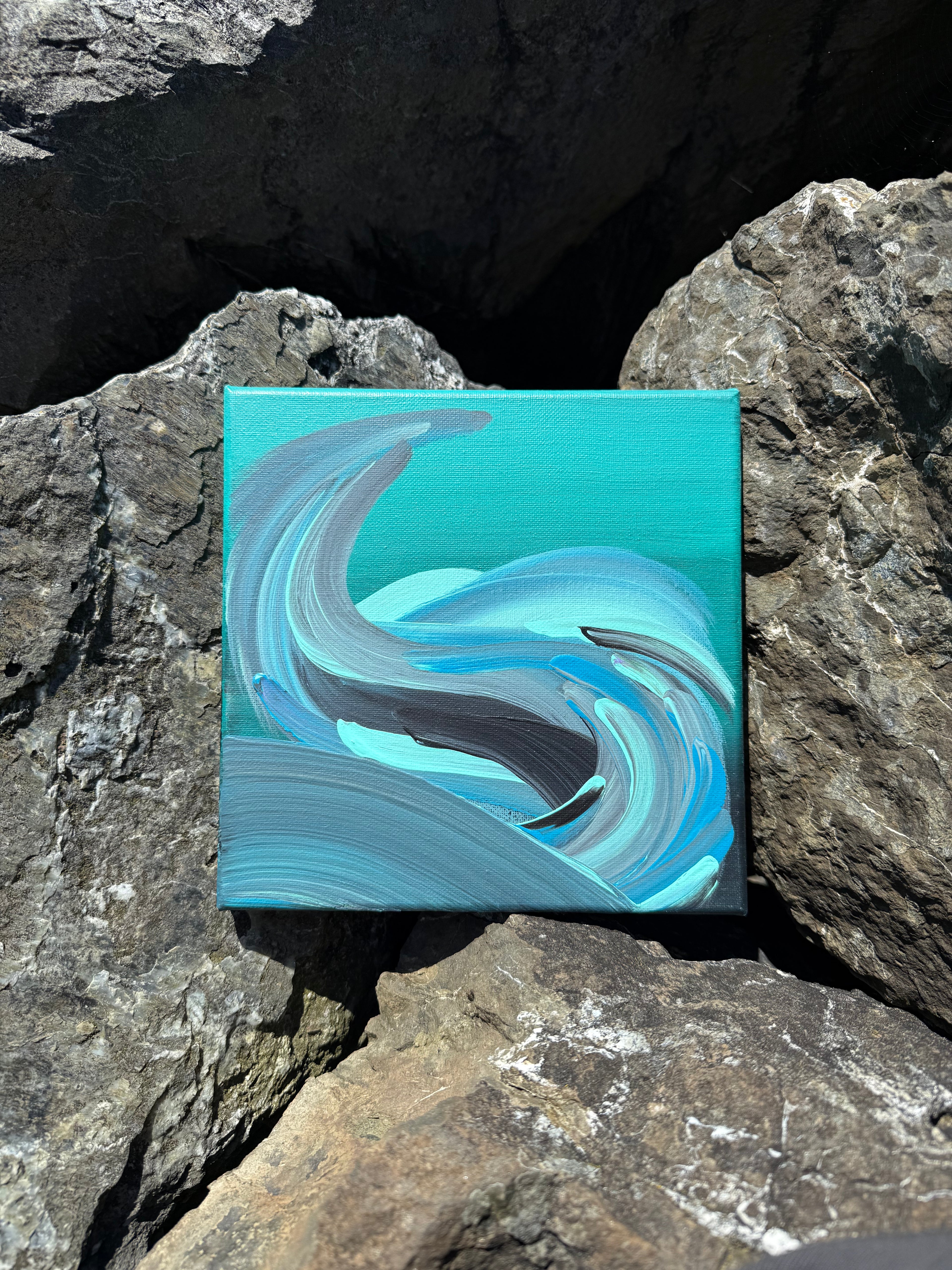 Abstract painting on a small canvas placed on rocks