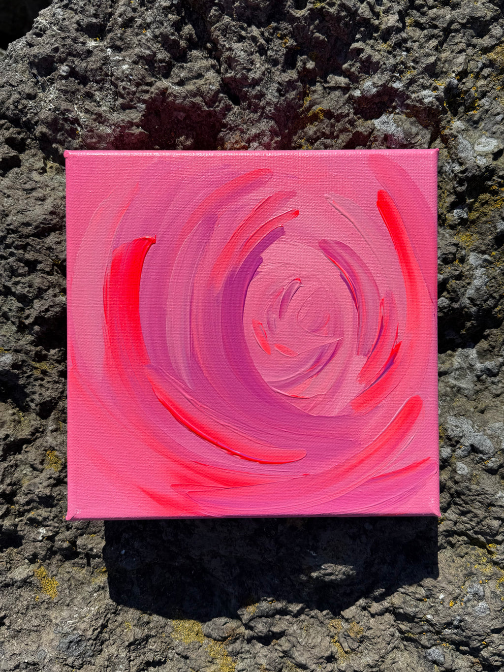 Pink spiral painting on a textured stone surface