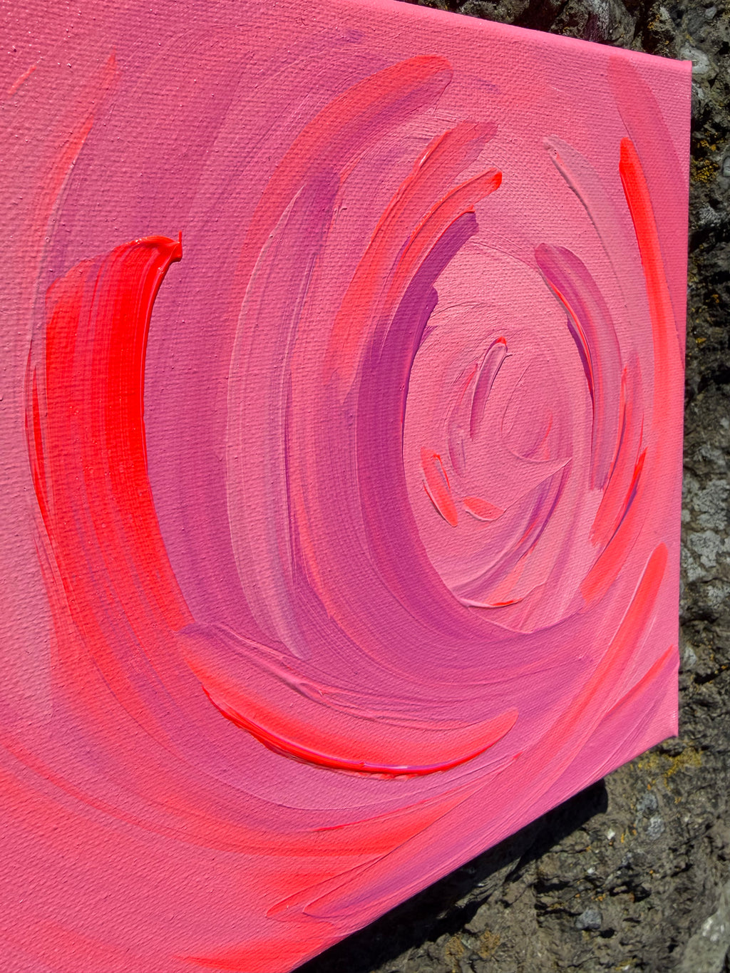 Pink and red abstract painting on a textured surface