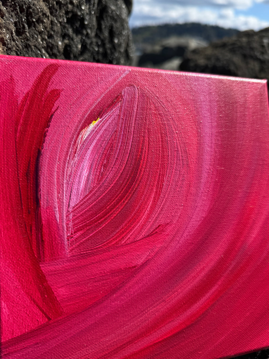 Close-up of a red abstract painting with swirling patterns on a textured surface.